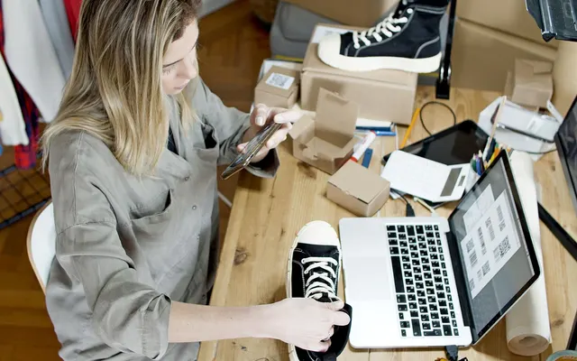 Ιδιοκτήτρια e-shop φωτογραφίζει προϊόντα δίπλα στο laptop